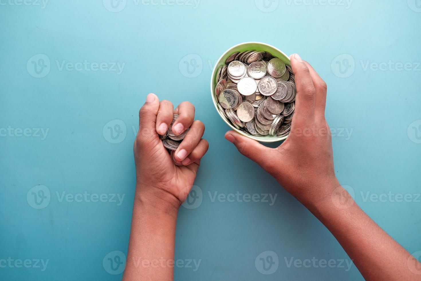 Joven ahorrando monedas en un frasco situado en blanco foto