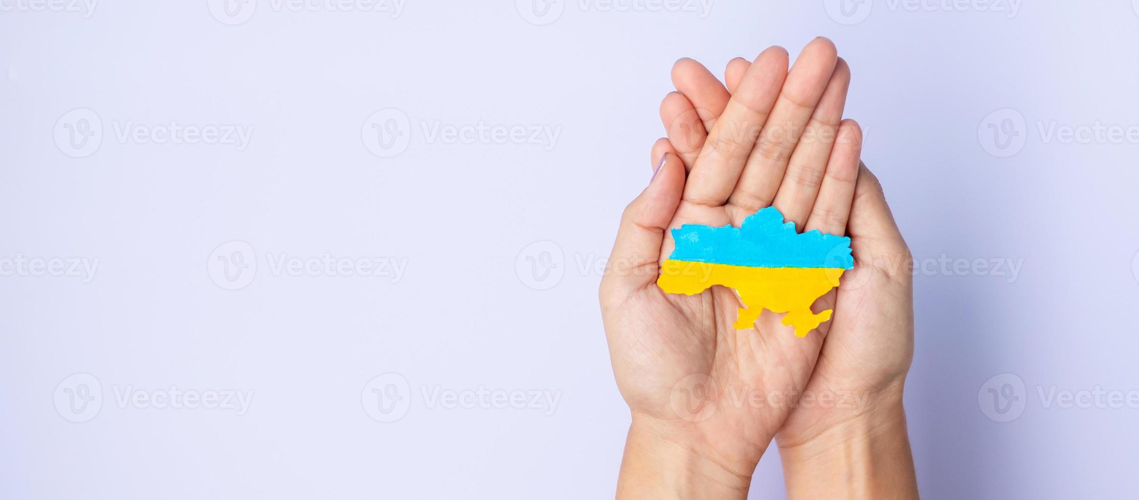 Support for Ukraine in the war with Russia, Hands holding the shape of Ukraine border with color flag. Pray, No war, stop war and stand with Ukraine photo