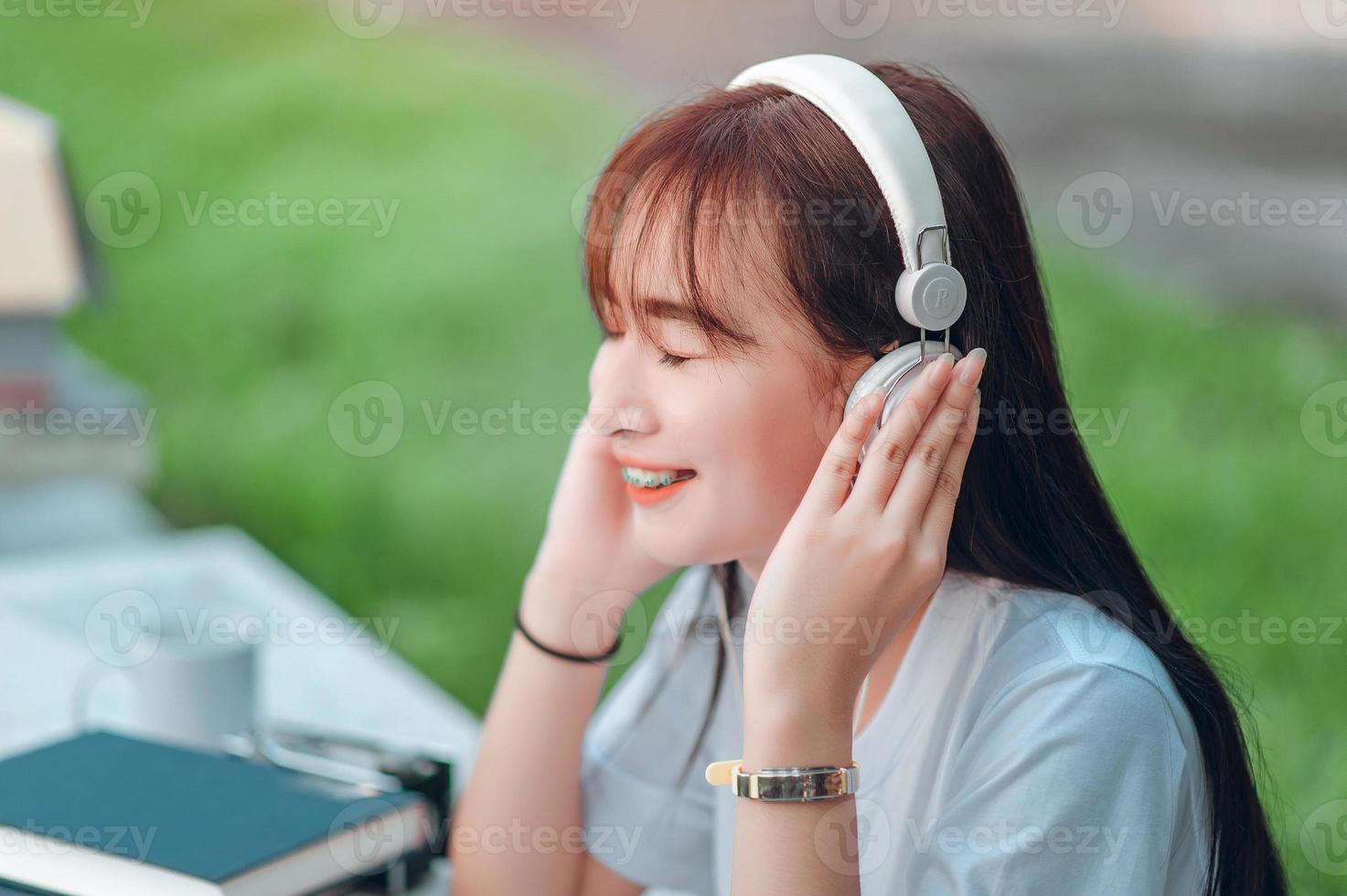 escuchando música. una hermosa mujer con auriculares se relaja en su escritorio. cierra los ojos y medita, medita. ella está escuchando música usando su concepto de teléfono inteligente, relajación y relajación. foto