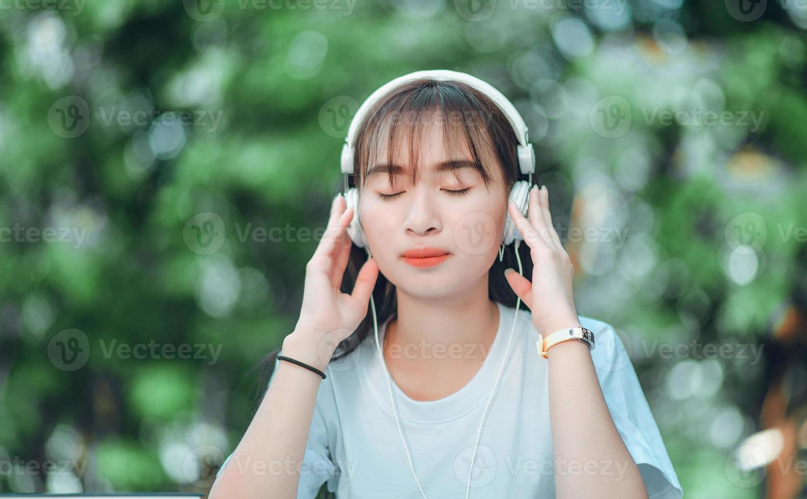 Listening to music. A beautiful woman with headphones is relaxing on her desk. Close your eyes and meditate, meditate. She is listening to music using her smartphone, chill and relaxation concept. photo