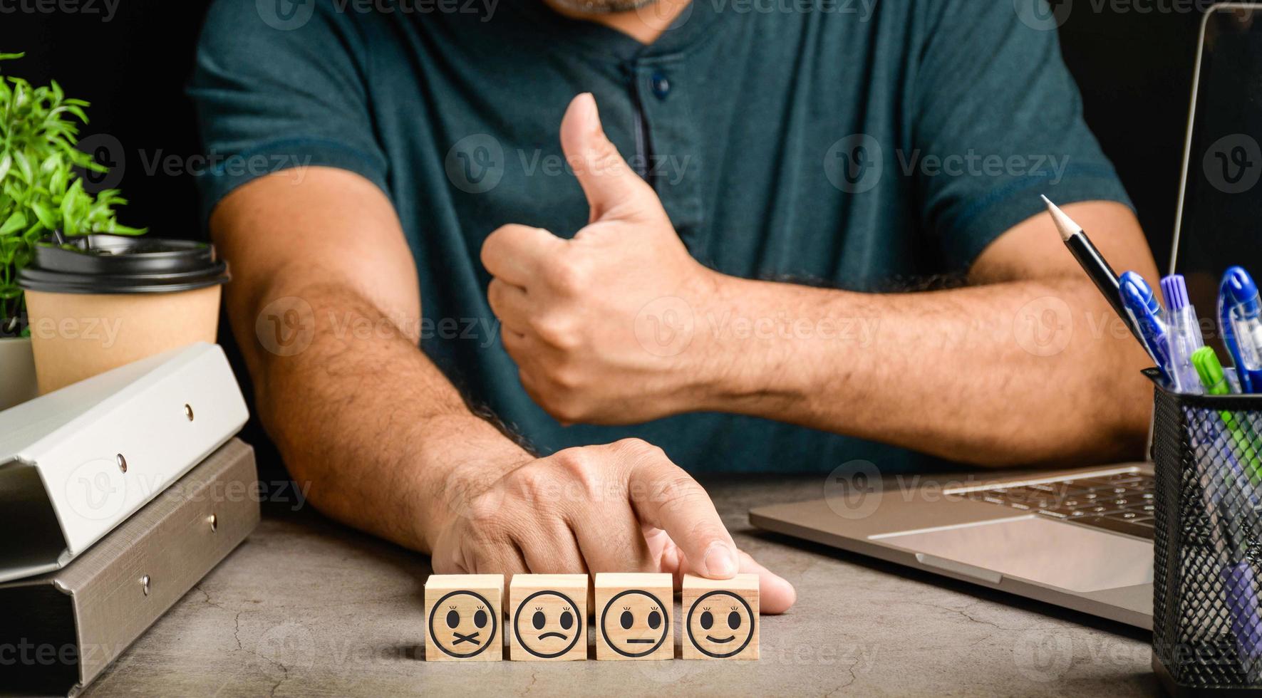 Blurred background, Businessman touch feedback with smile face wood cube happy Smiley face icon to give satisfaction in service. rating very impressed. Black, Customer service and Satisfaction concept photo