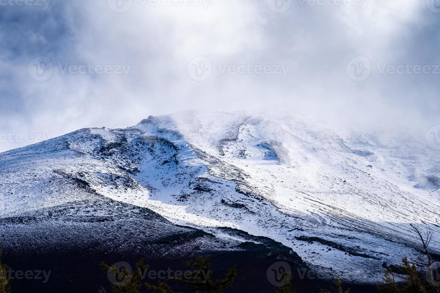 cierra la cima de la montaña fuji con cubierta de nieve y viento en la cima con podría en japón. foto