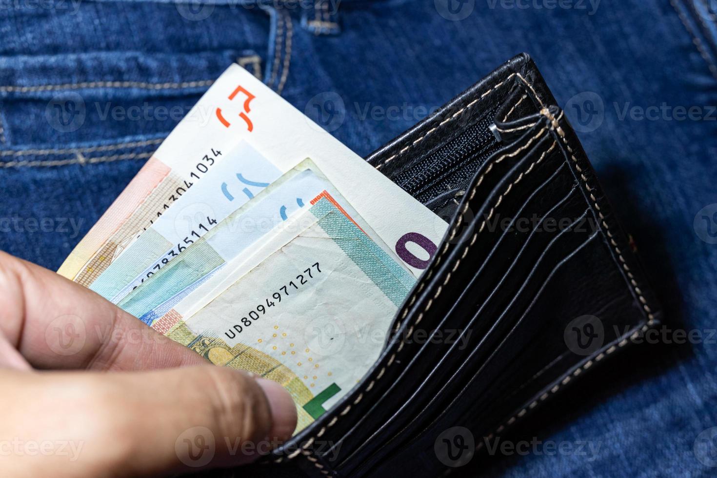 dinero en euros, billete en euros dentro de una cartera de cuero negro sobre fondo de jean. foto