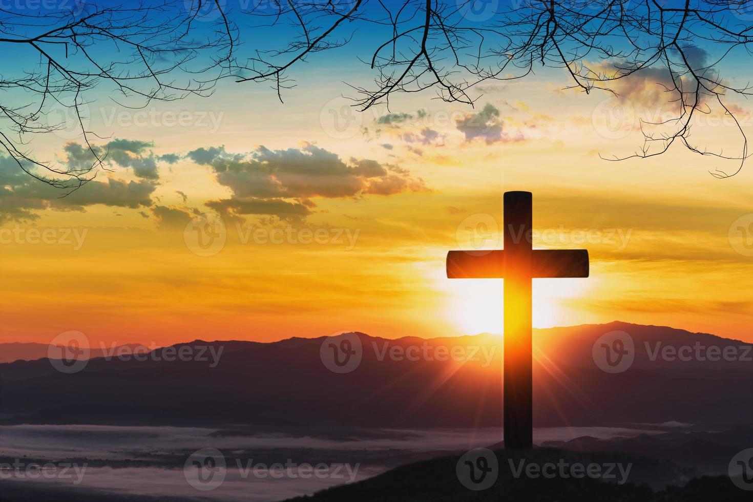 silueta de cruz en la montaña con fondo de puesta de sol. foto