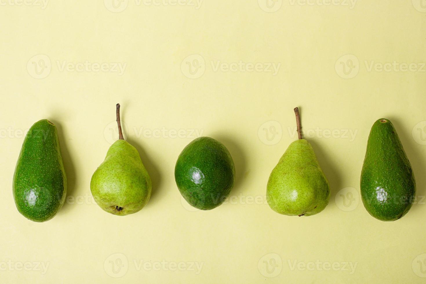 Flat lay of assorted fresh green fruits avocado and pear on yellow background photo