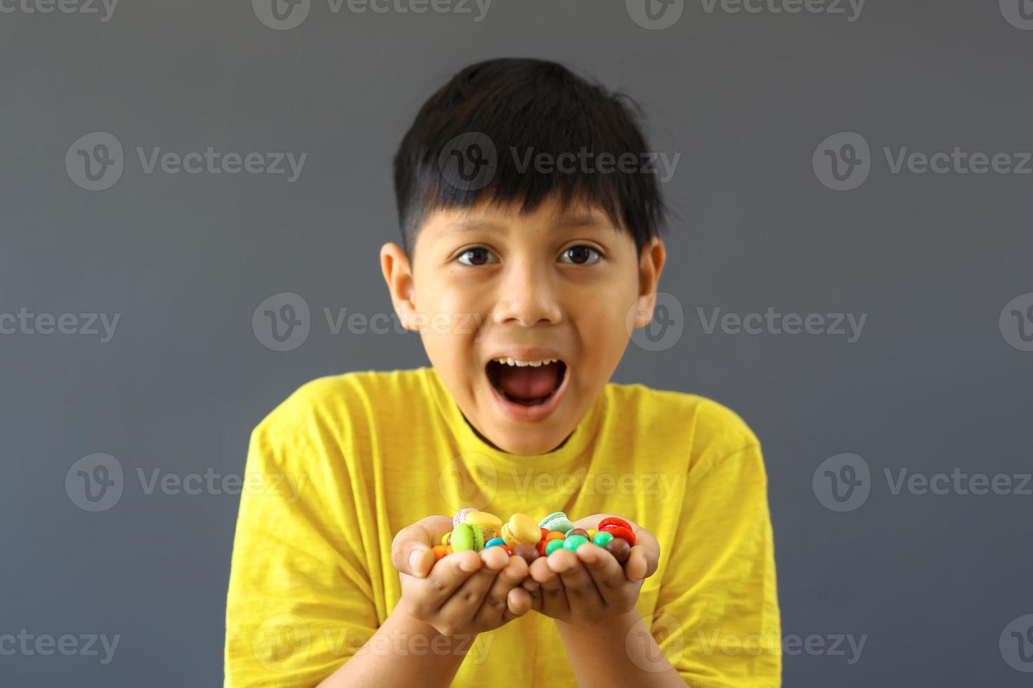 Happy kid with hands full of assorted colorful candies photo