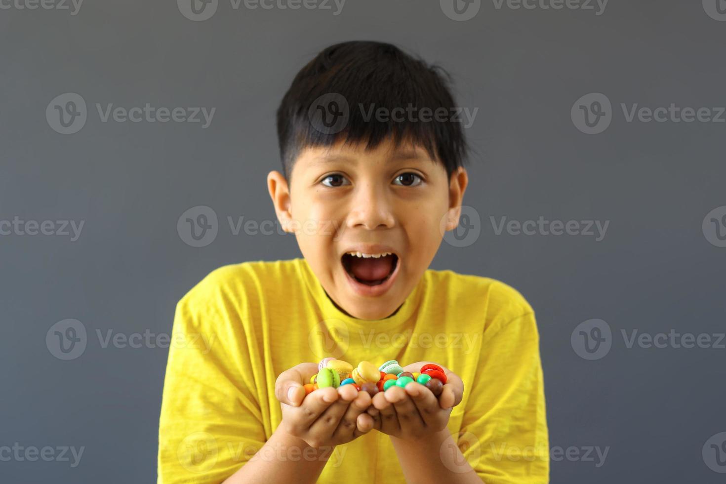 niño feliz con las manos llenas de caramelos de colores surtidos foto