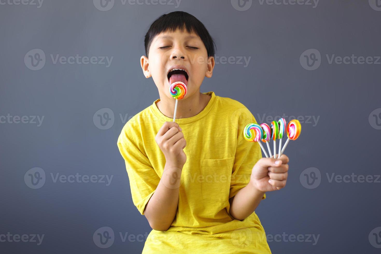 chico asiático lamiendo un caramelo de piruleta foto