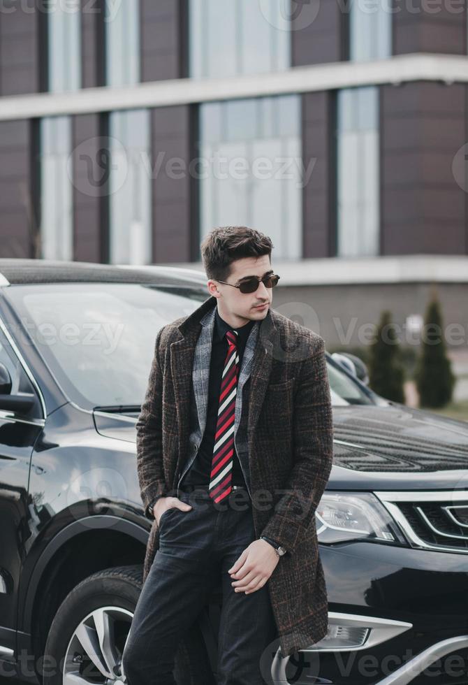 businessman in glasses standing near automobile photo