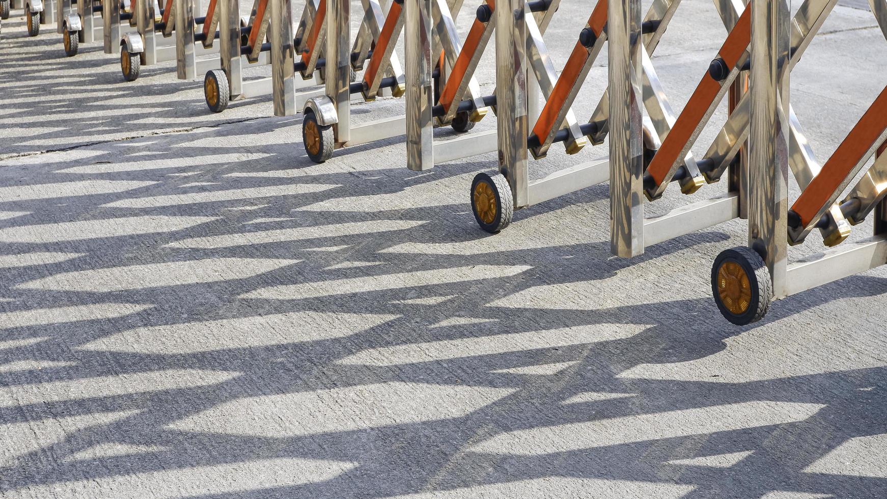 Low section of stainless steel barrier gate or folding fence gate with sunlight and shadow on the street in perspective side view photo