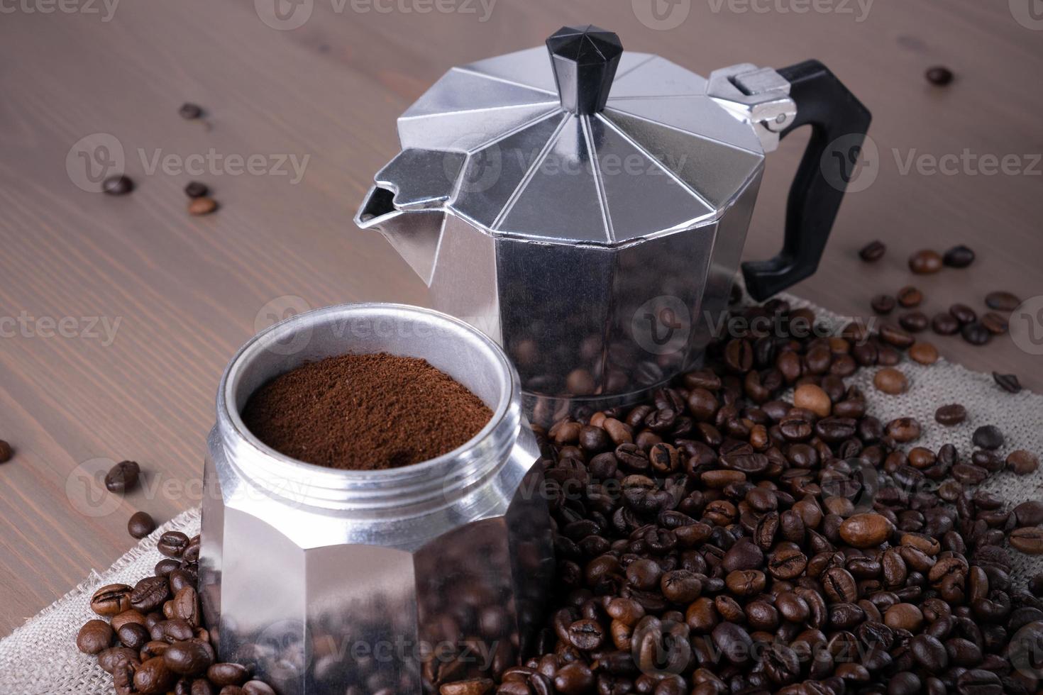 Disassembled geyser coffee maker on wooden surface. Coffee beans. photo