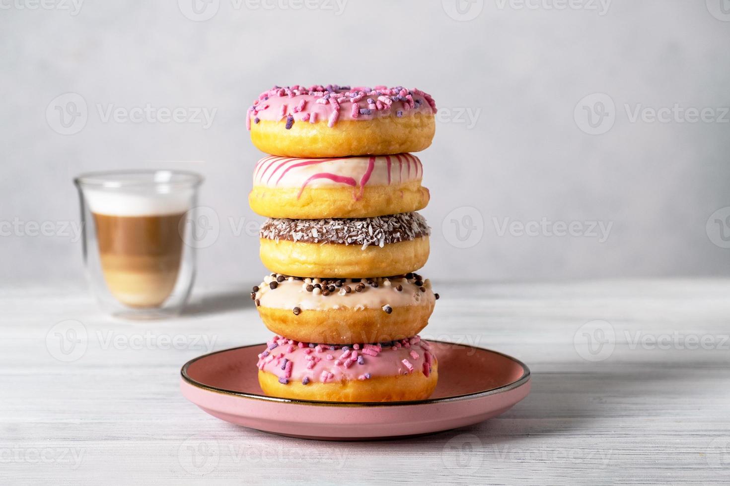 donuts decorados glaseados en platos y café con leche o capuchino foto