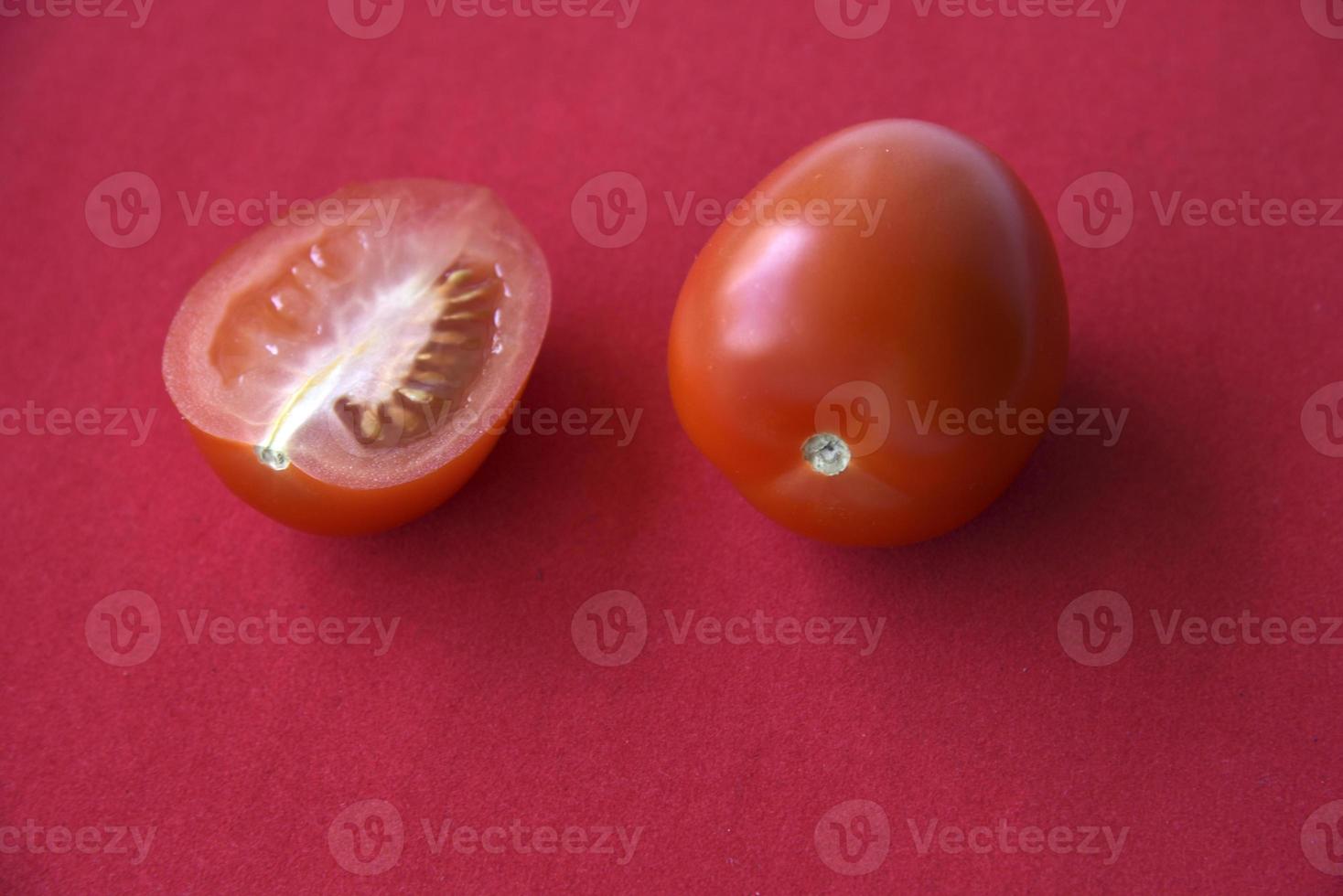 Juicy tomato on a red background photo