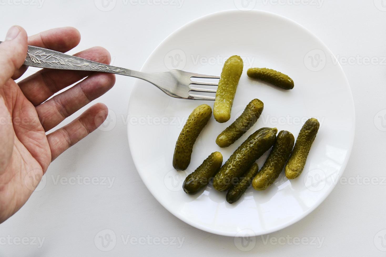 Green pickles on a white plate and a fork photo