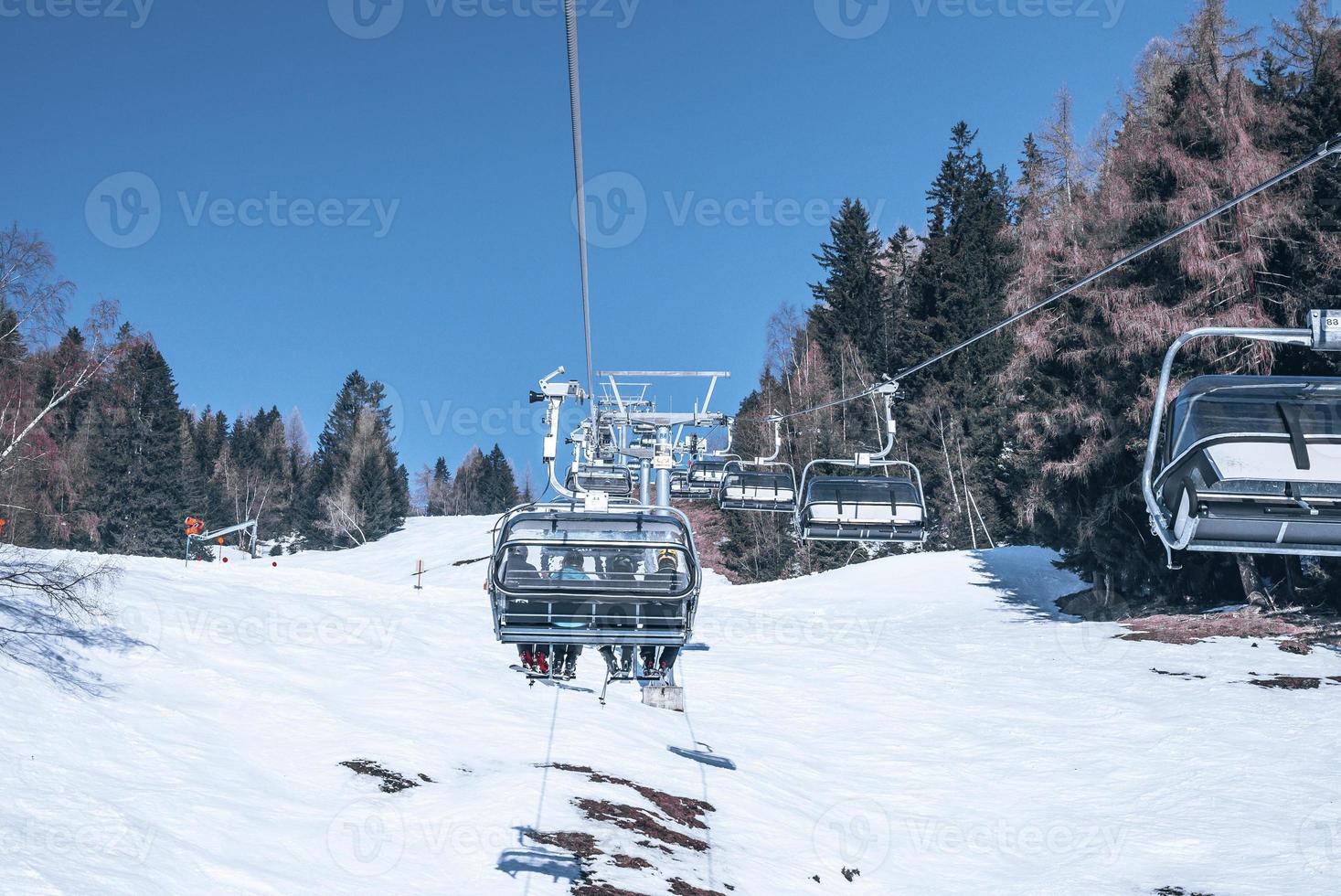 Skiers enjoying on ski lift over snowy mountain landscape photo