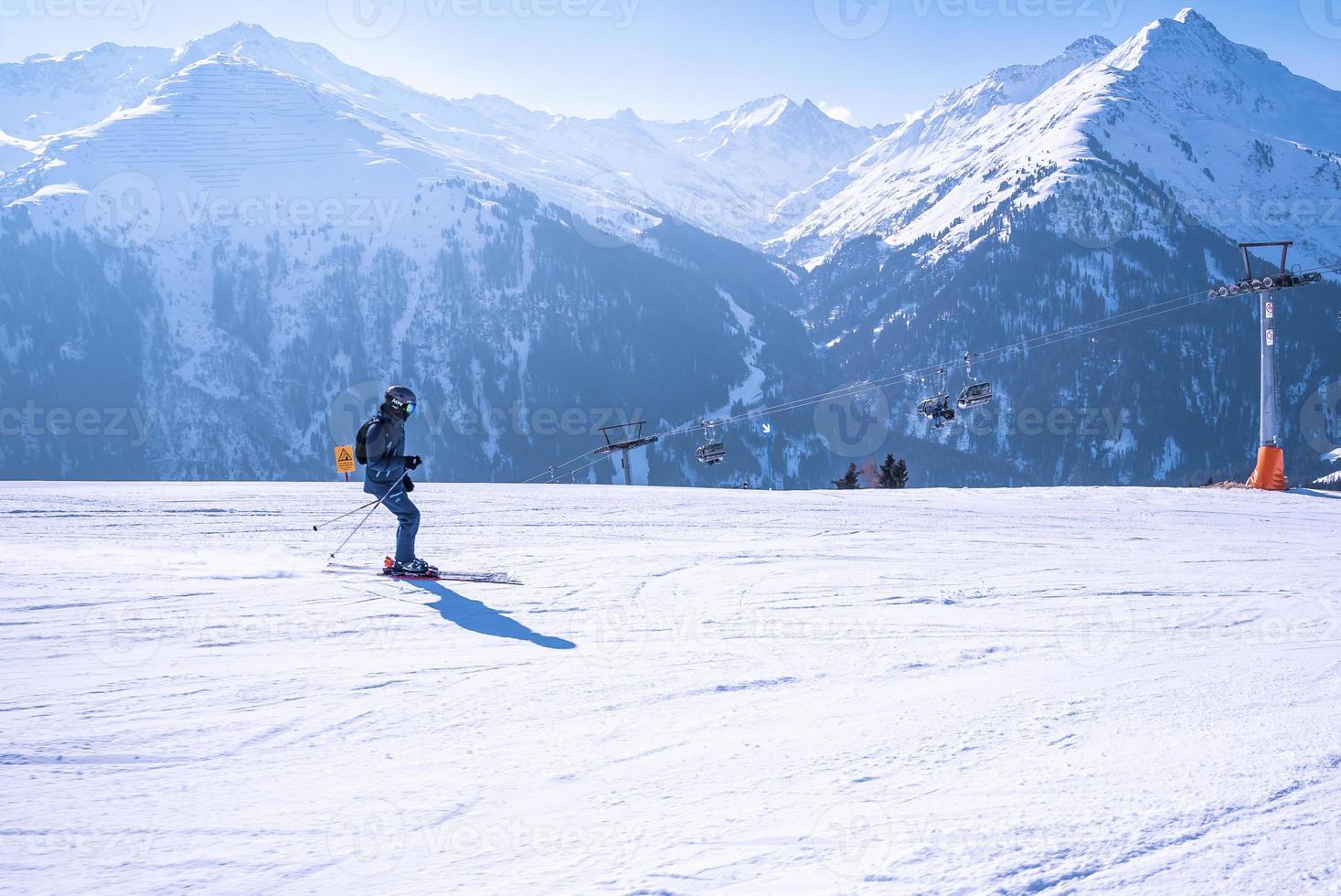 Skier in sportswear skiing on mountain against ski lift in cold weather photo