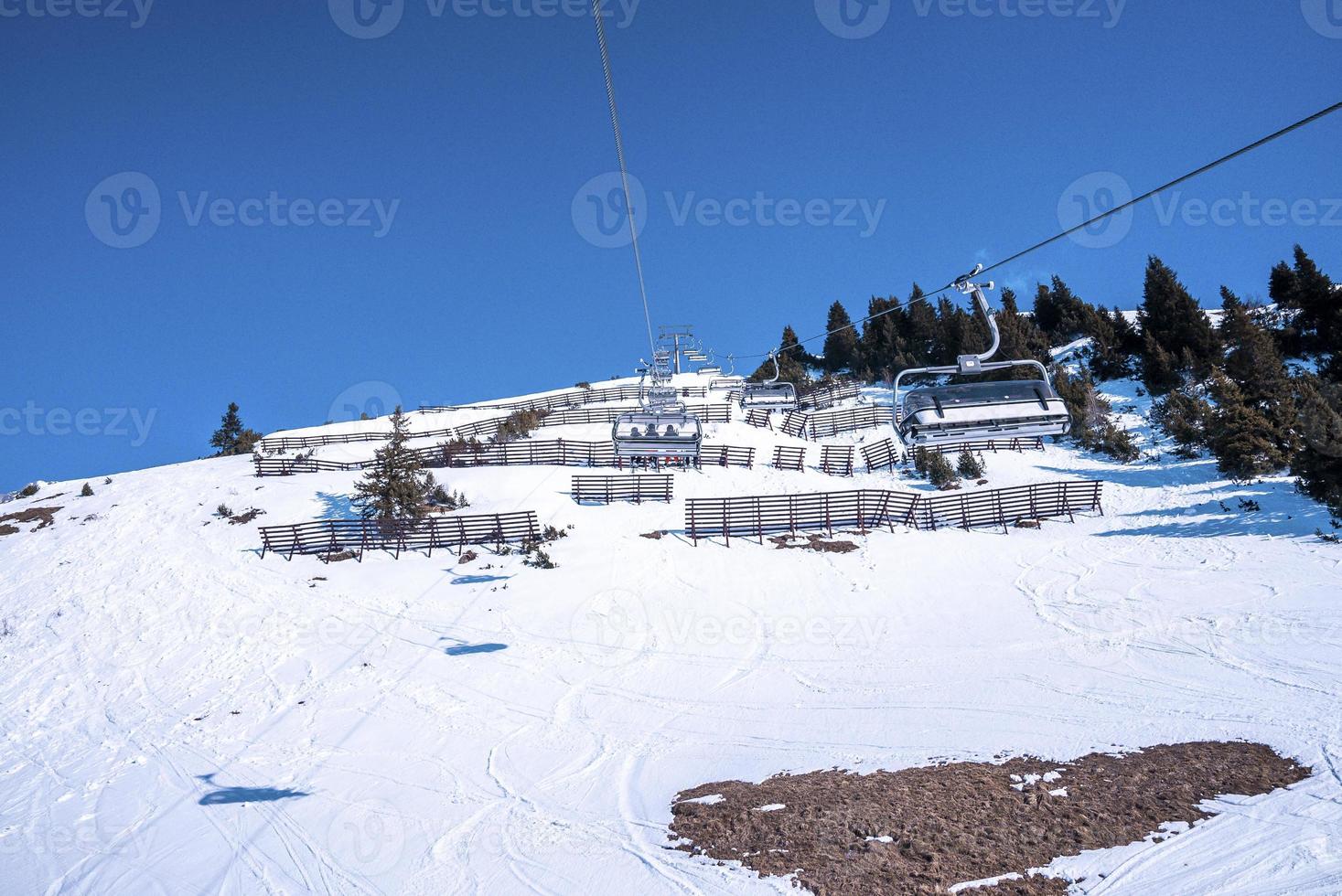 telesilla sobre la pintoresca ladera de la montaña cubierta de nieve contra el cielo azul foto