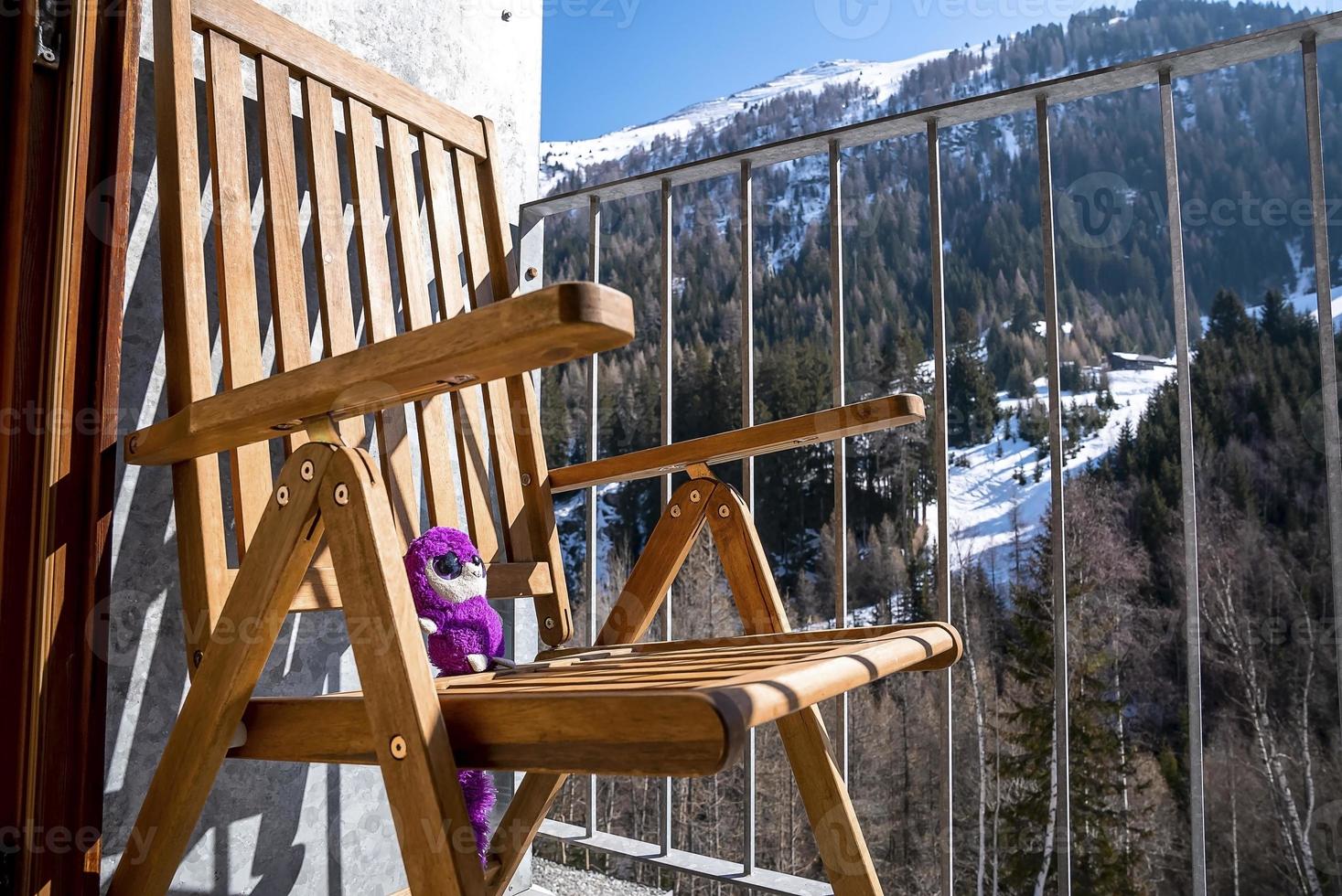 juguete de peluche suave disfrutando de la luz del sol en una silla en el balcón del resort foto