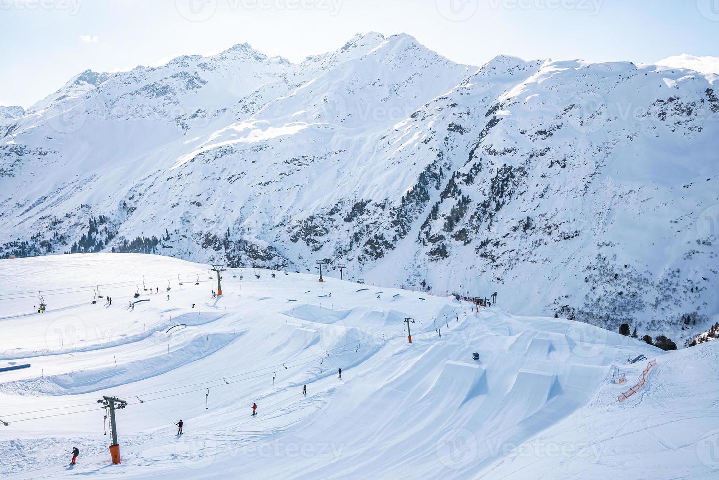 View of tourists enjoying winter sport on snow covered alps photo