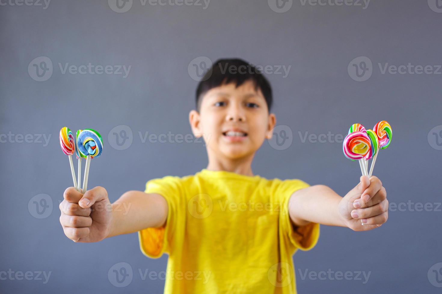 niño asiático feliz sosteniendo piruleta foto