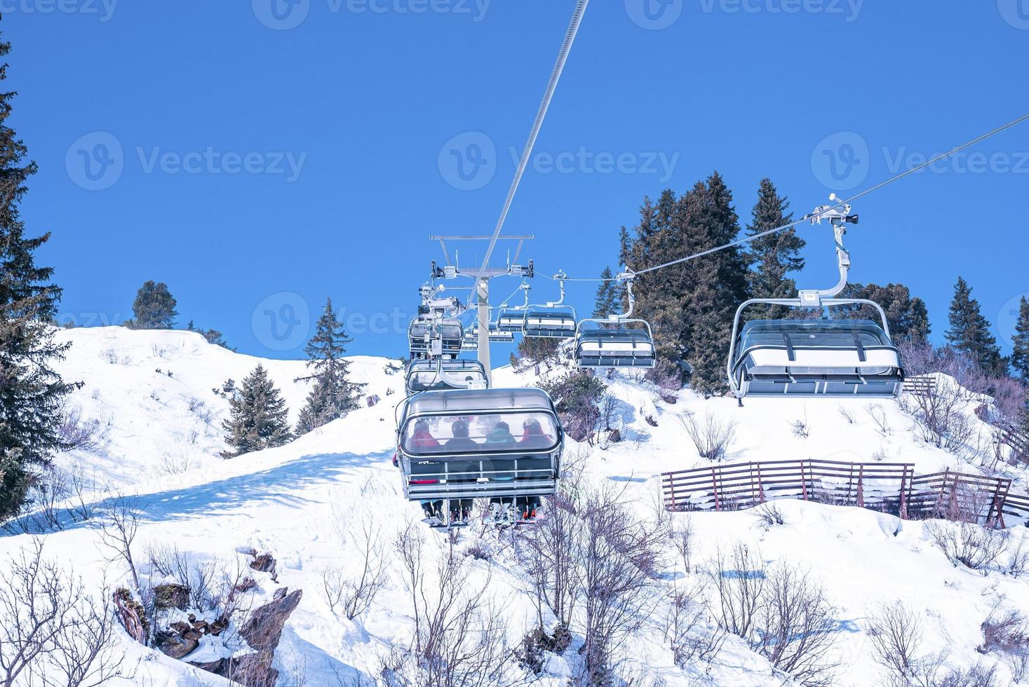 Ski lift over scenic snow covered mountain against clear blue sky photo