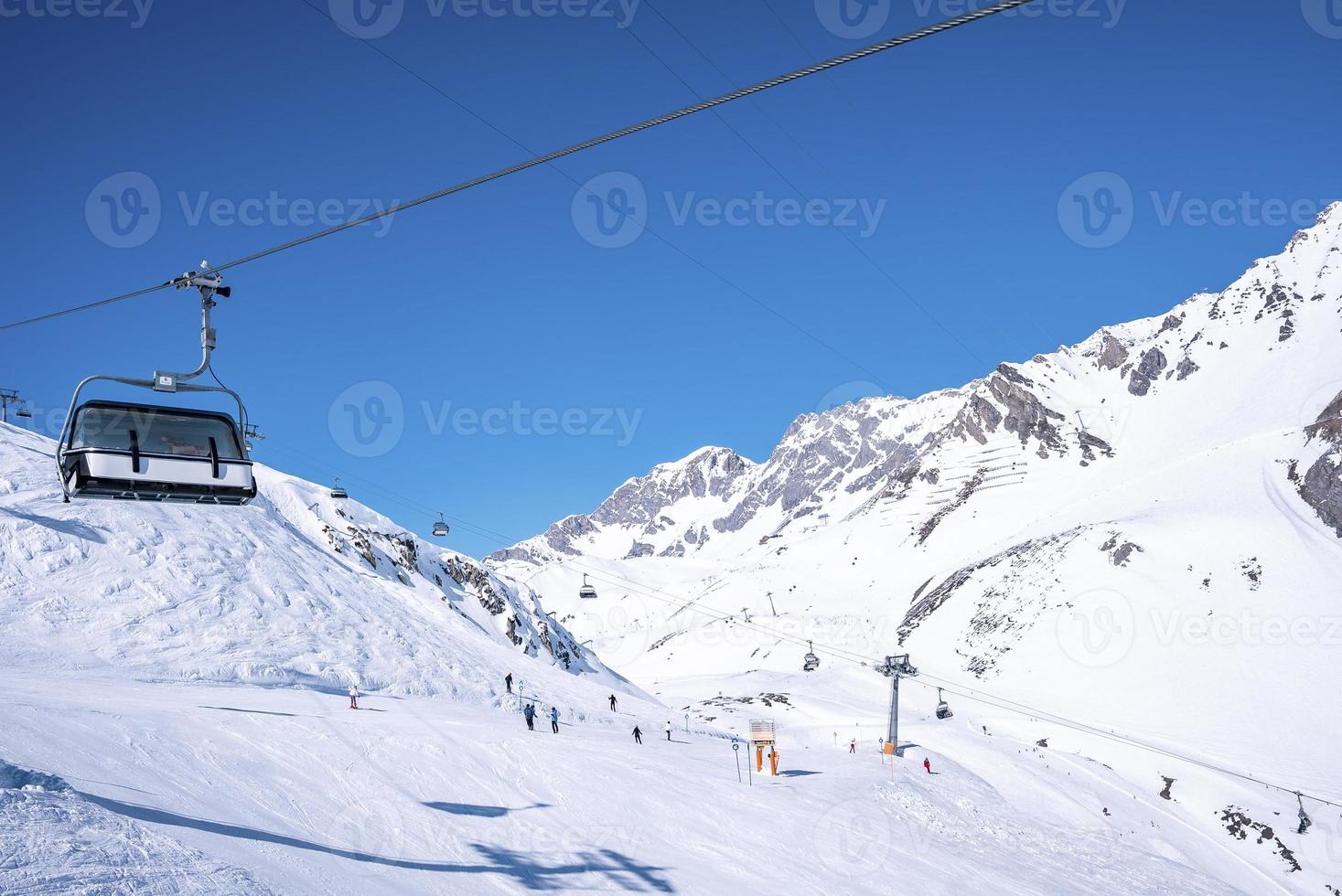 telesilla que viaja sobre montañas cubiertas de nieve contra el cielo azul claro foto