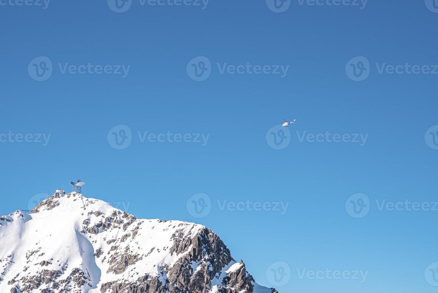 Rescue helicopter flying over snowy mountain photo