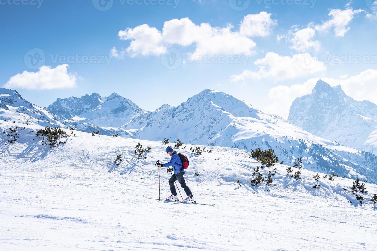 Skier skiing on snowy landscape against mountain range photo