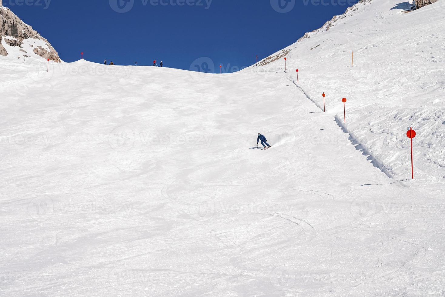 Distant skier sin sportswear skiing on snowy mountain against sky photo