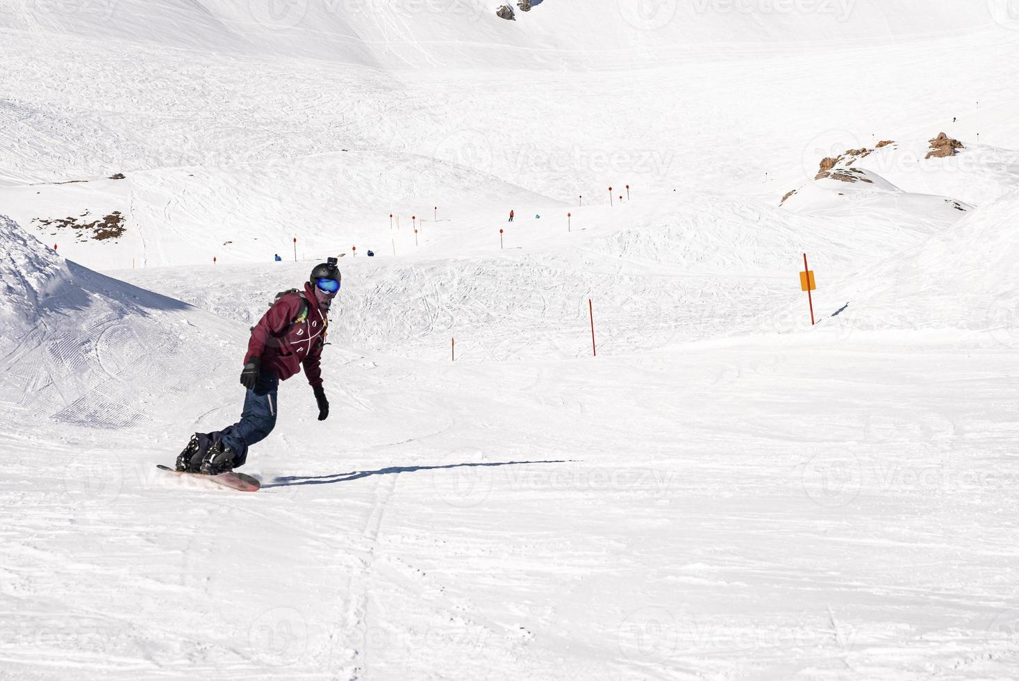 Young snowboarder sliding down snowy slope on mountain at winter resort photo