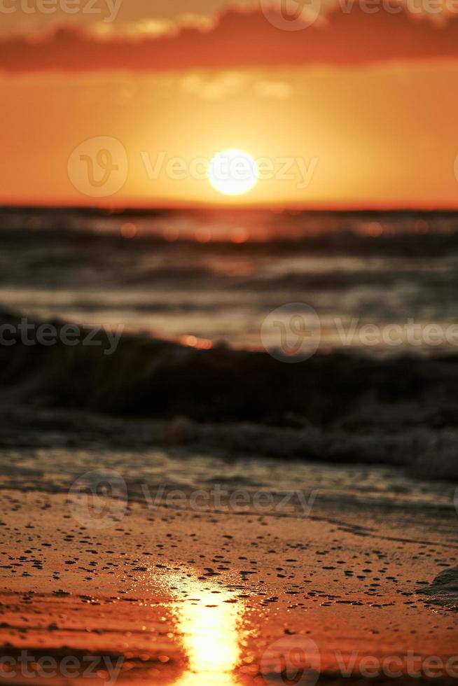 Sunset light reflection on sea sand surface, beautiful yellow sunlight in sea foam, warm sandy beach photo