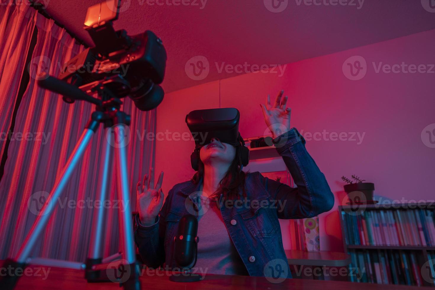 Beautiful Hispanic woman in front of a video camera recording a blog in her studio with red and blue lights inside her house photo