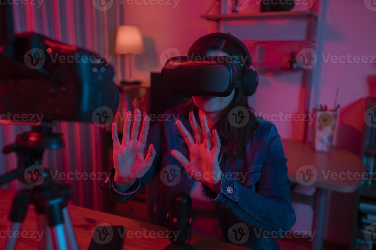 Beautiful Hispanic woman in front of a video camera recording a blog in her studio with red and blue lights inside her house photo