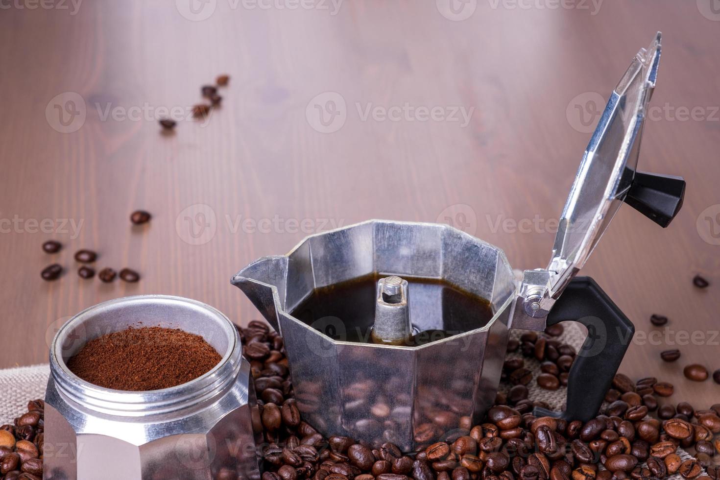 cafetera de géiser desmontada sobre superficie de madera. granos de café. foto