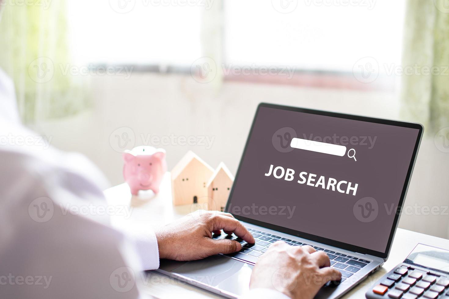 A man sits and typing keyboard to job search in the work at home. Find work with a laptop computer and put it on the white table in living room. Concept of business service survey. Blurred background photo