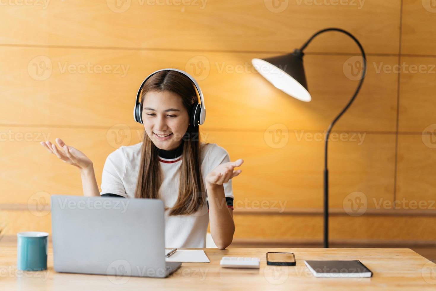 mujer joven asiática sonriente usando auriculares mirando la pantalla del portátil escuchando y aprendiendo cursos en línea. mujer de negocios china feliz con videollamada de auriculares para servicio al cliente foto