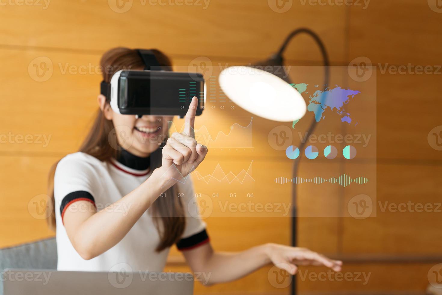 Conceptual image of confident and successful business woman in suit sitting inside office building with financial interface and using virtual reality headset. photo