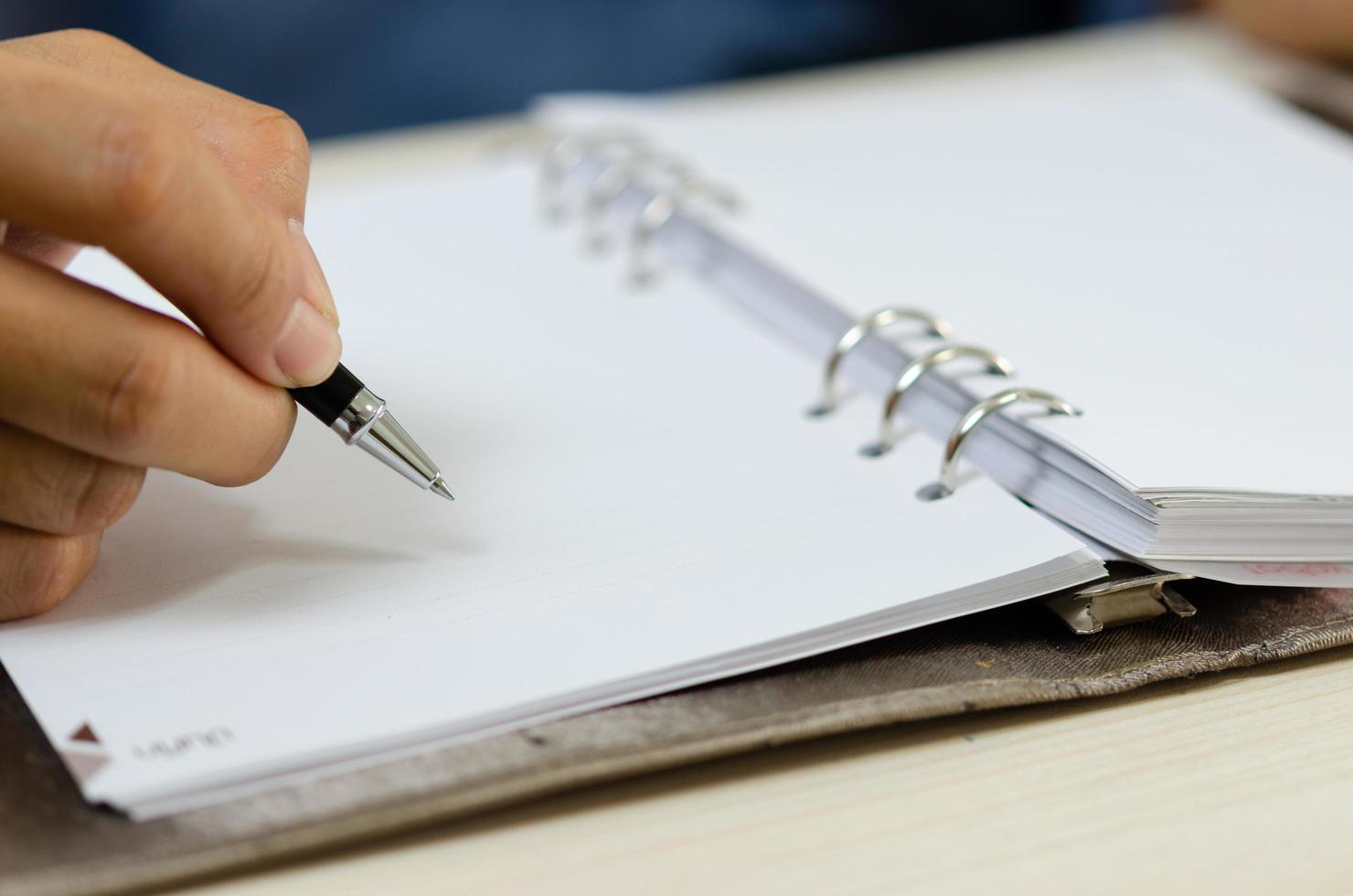 close up holding a pen and writing at the notebook. photo