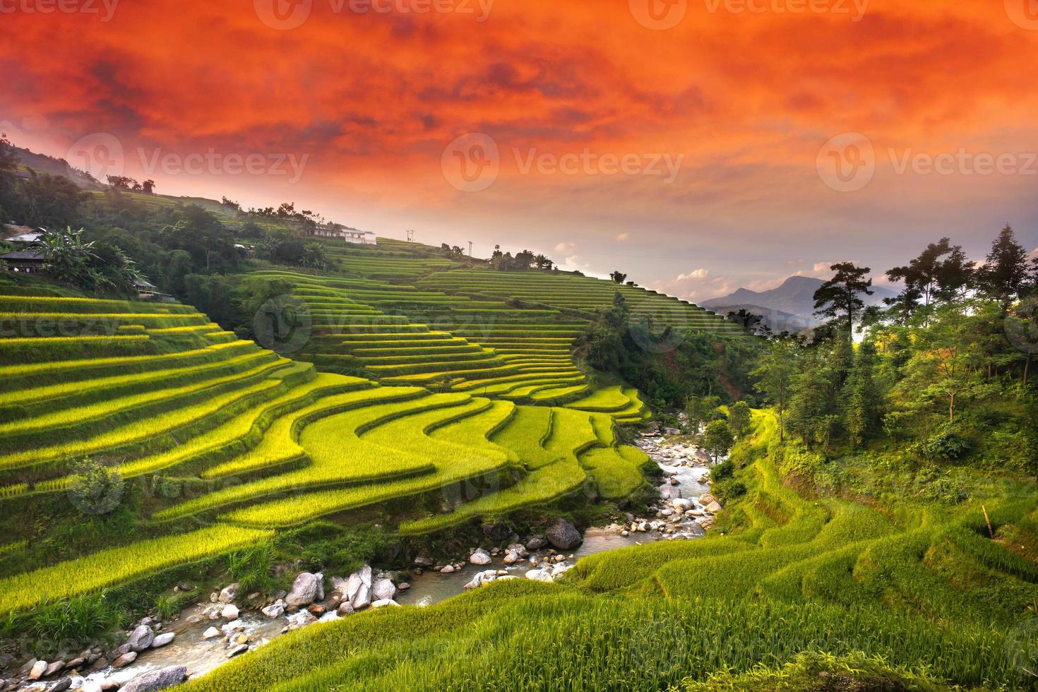 hermoso campo de arroz con río entre colinas y montañas y cielo anaranjado tranquilo en un hermoso amanecer. foto