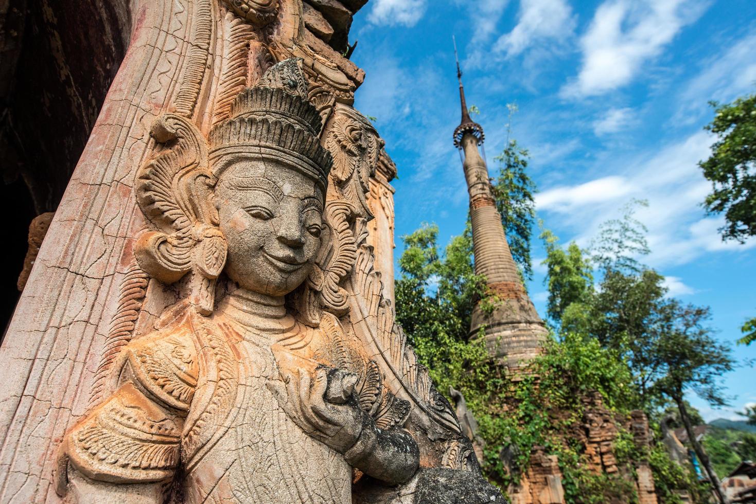 la estatua del ángel guardián parada frente a la antigua pagoda en el lago inle de myanmar. foto