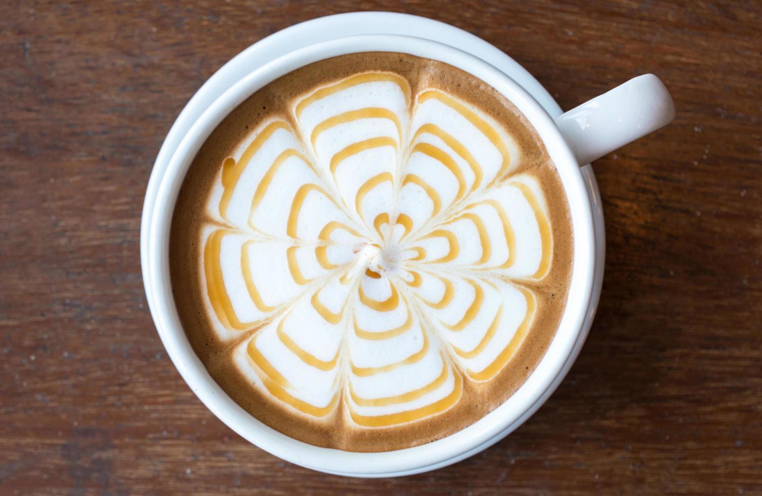 Closeup of Latte coffee art with caramel on the water surface serving on the wooden table. photo