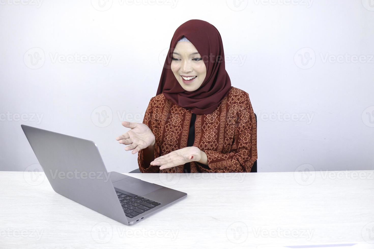 Young Asian Islam woman is smiling pointing hand when working on laptop on white background. photo