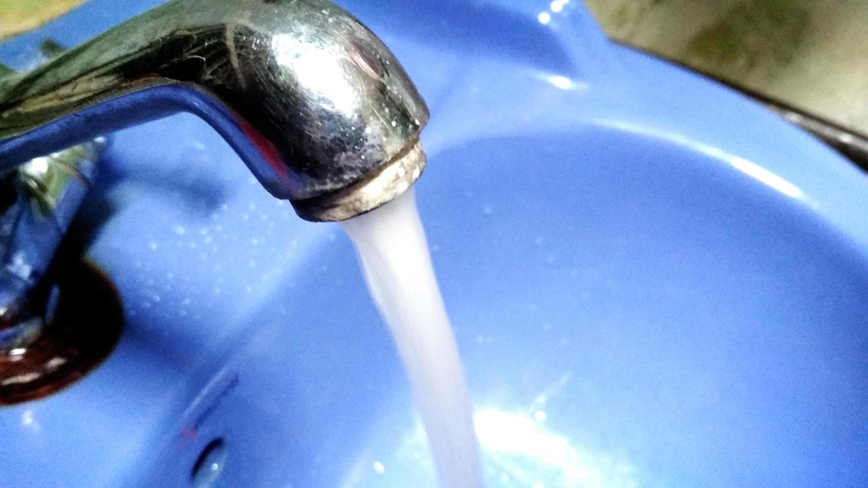 Water runs from a metal water tap. Close up photo
