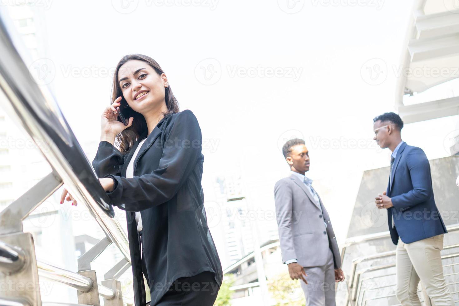 Business woman using communication device in city. Business team and teamwork concept. Business people standing outside in the city discussing about new project. photo