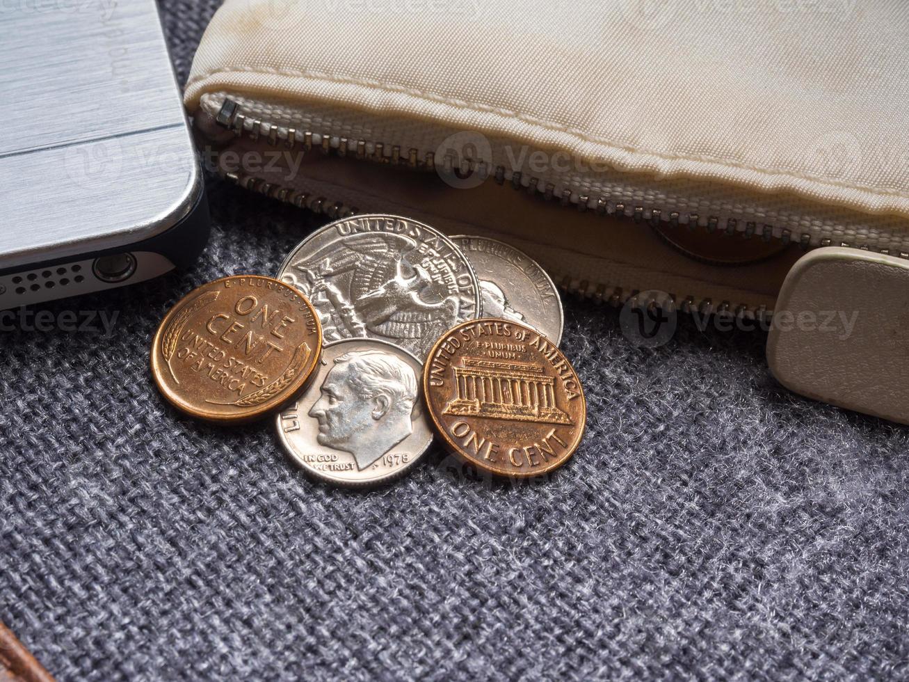 US dollar coins placed outside the wallet with smartphone. photo