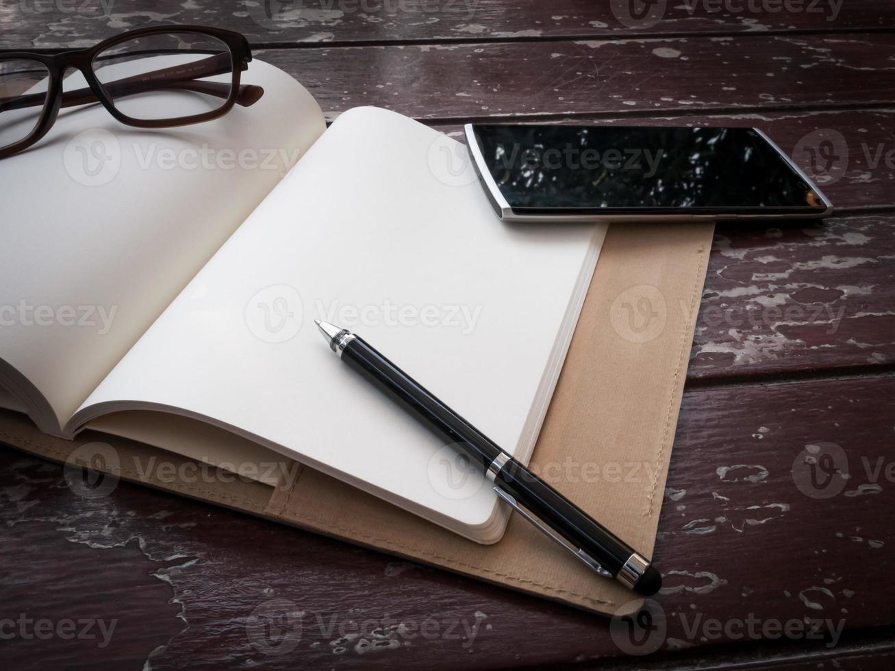 Workspace with glasses, pen and smartphone, note paper and notebook on old wooden table photo