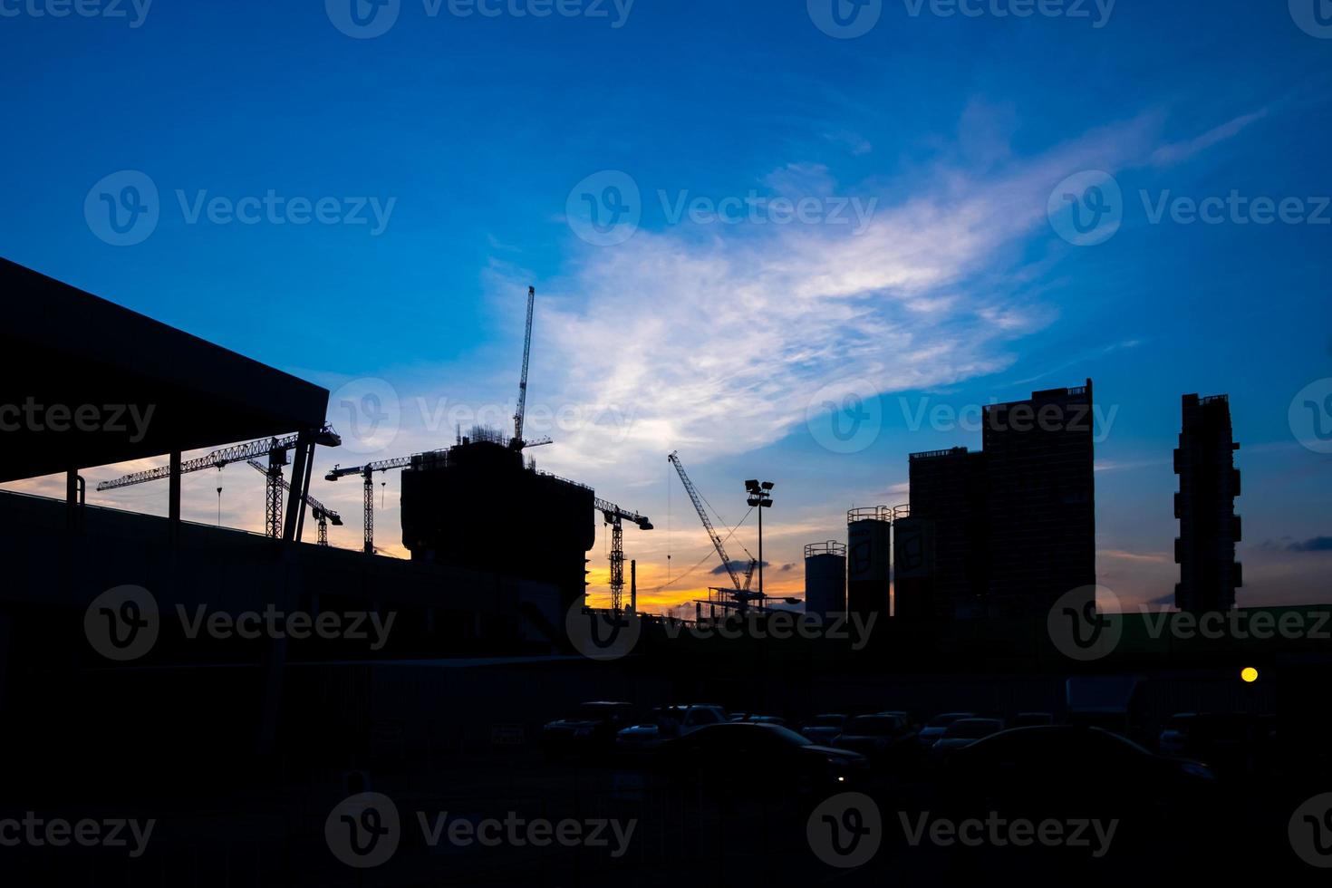 Industrial construction cranes and building silhouettes over sunset photo