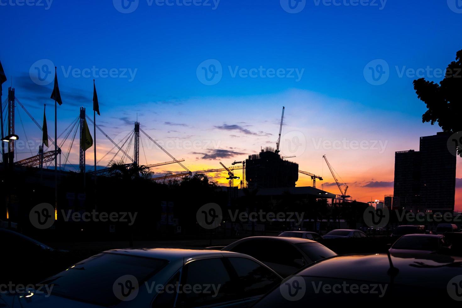 Industrial construction cranes and building silhouettes over sunset photo