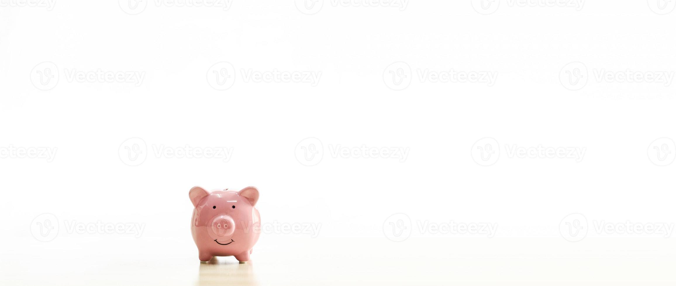 A pink piggy bank is placed on the table. The concept for financial, business, banking, save, loan, invest, budget, account, nobody, no people. Copy space on right for design or text white background. photo