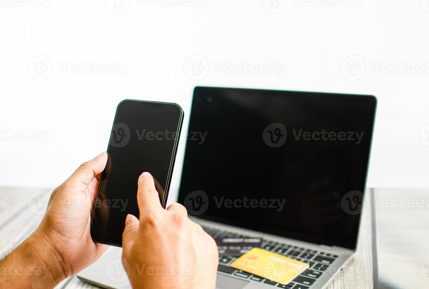 Men use smartphones to shop online. Businessmen transfer money via the Internet. A man's hand holds a smartphone to payment. Business people use laptops on a desk. Selective focus. Blurred background. photo